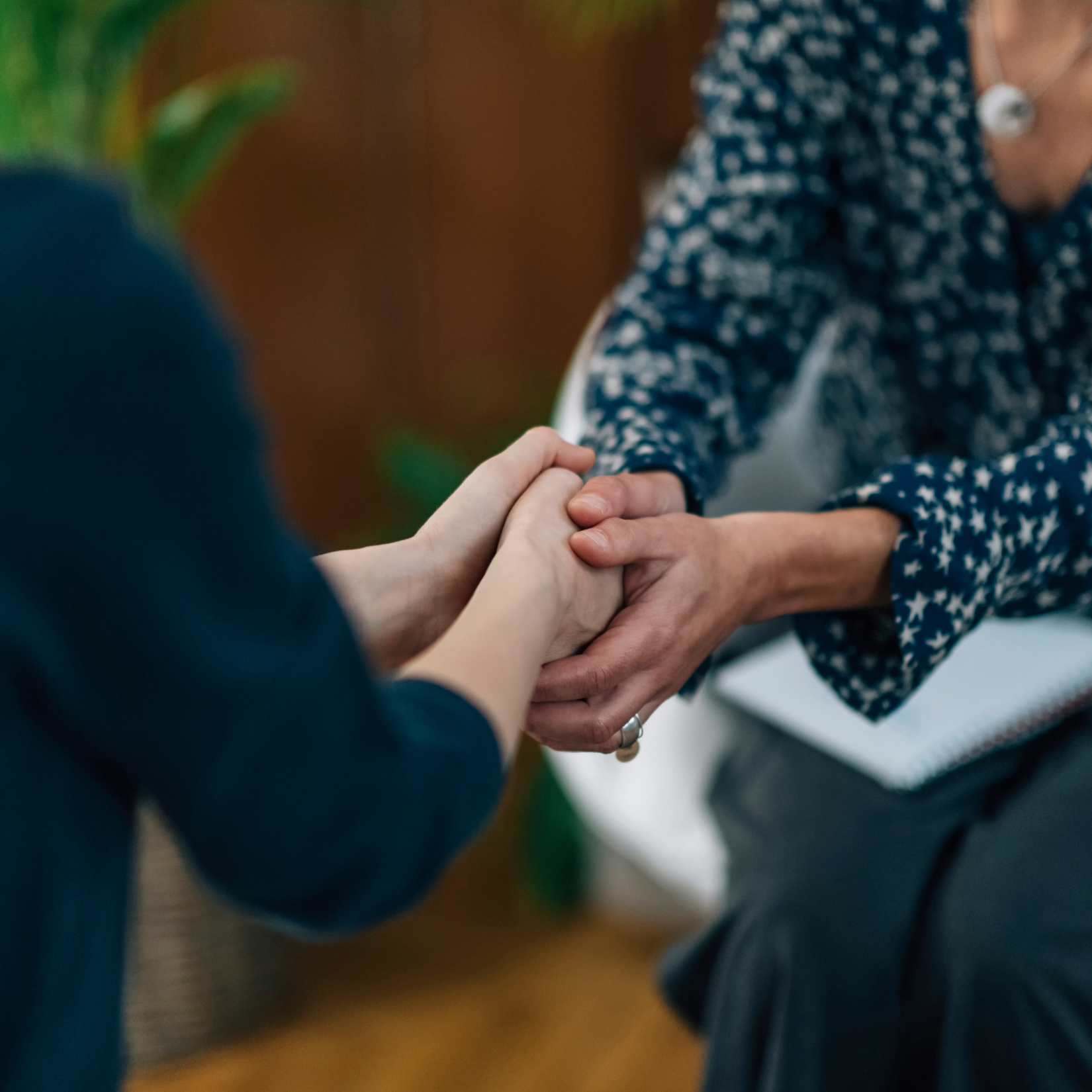 Life coach holding a client's hands during a supportive session